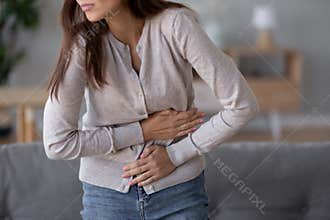 Young sick woman standing holding belly suffering from stomach pain