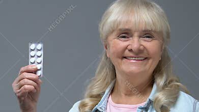 Happy old woman showing pills blaster, health care, disease treatment, vitamins