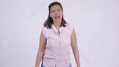 Young angry Asian businesswoman shouting and pointing at camera