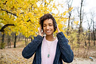 Africanamerican girl listening to music in the autumn park