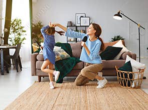 Happy family mother and child play at home and sing with combs