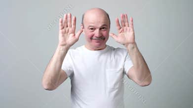 Senior bald man saying bye to his friends waving his hands.