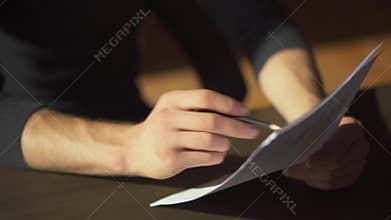 Male hands making paperwork with writing amendments in documents close up. A businessman studies graphics and makes