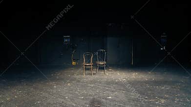 There are two chairs on an empty theater stage. The end of the play