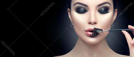 Beautiful fashion model woman eating black caviar. Beauty girl with caviar on her lips