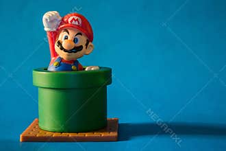 Super Mario with pipe toy figure. There are plastic toy sold as part of the McDonald`s Happy meals. Isolated on blue background.