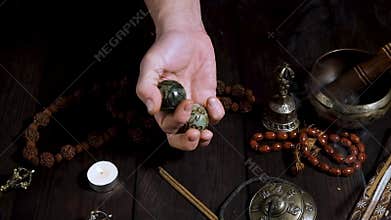 Two stone balls in male hands and other Tibetan instruments