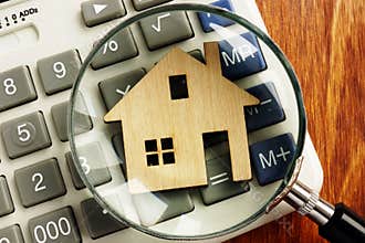 House value. Model of home and magnifying glass