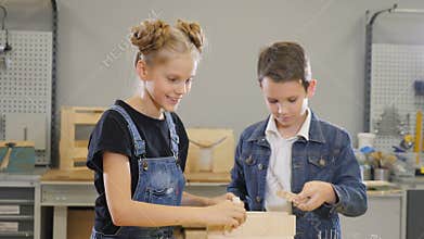 Children play at craft workshop. Cute little boy and his school-aged sister playing with wooden semi-finished pieces