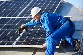 Electrician mounting solar panel on roof of modern house