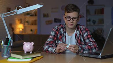 Teenager counting dollar bills and putting them to piggyback, first salary