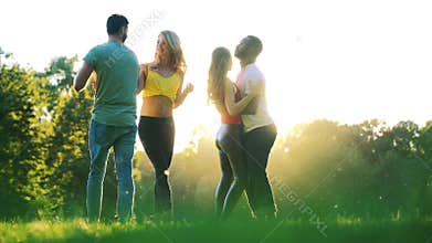 Women and men having fun dancing in the park