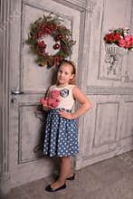 Girl blonde child with a pink teddy bear in hand with a Christmas wreath