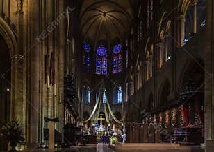 The pulpit, the altar and the cross of the Notre Dame de Paris Cathedral with the stained glass windows along the back wall in
