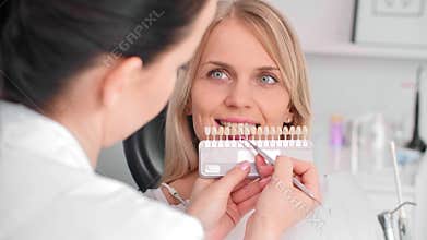 Close up of dentist choosing color teeth from palette