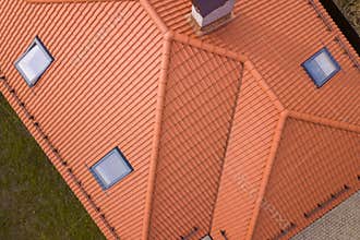 Aerial top view of house metal shingle roof, brick chimneys and small plastic attic windows. Roofing, repair and renovation work
