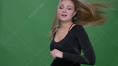 Portrait of delighted businesswoman in black blouse dancing joyfully and actively at green background.