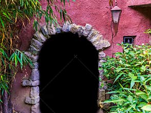 Medieval looking arch doorway with a lantern, castle architecture, dark door opening in a wall