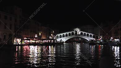 Venice, night illumination, famous Rialto Bridge, Italy. Beautiful view of the Grand Canal at night. Reflections on the