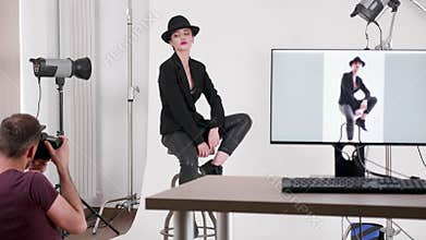 Backstage of professional photo shoot where photographer is taking pictures of the model
