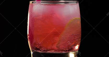 Making a refreshing red drink cocktail in a glass with ice, and lime