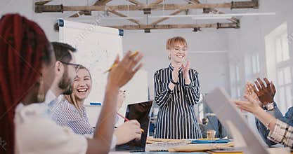 Beautiful young Caucasian CEO businesswoman giving a motivation speech to happy multiethnic team at office meeting.