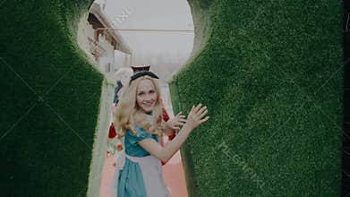 Alice and the Hatter from Alice in Wonderland look into the camera directly at the audience and then run along the fabulous corrid