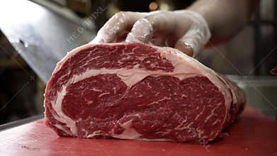 Butcher in gloves cuts carcass of red meat. Action. Close-up of professional knife cutting huge piece of meat in butcher