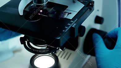 Hands in gloves research biochemistry material in laboratory using microscope.