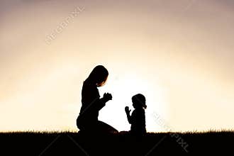 Mother Praying with her Young Child Outside at Sunset