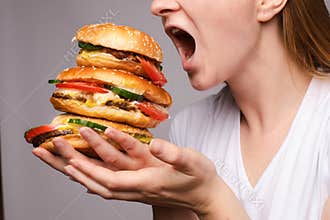 The woman opened her mouth to eat a hamburger