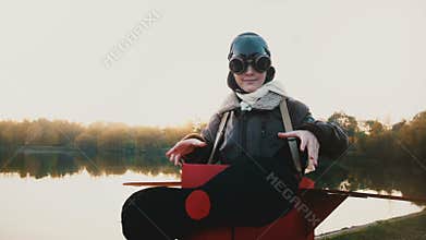 Beautiful portrait of happy little girl putting glasses on in fun plane pilot costume looking at camera slow motion.