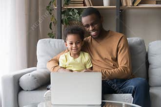 African father and little son watching cartoons on laptop