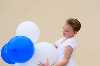 Happy little girl with blue and white balloons.
