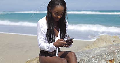 Woman with smartphone on coastal stone