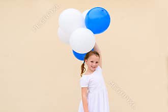 Happy little girl with blue and white balloons.