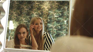 Young women checking their appearance and smiles in front of the mirror