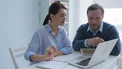 Office workers cooperating over project at laptop