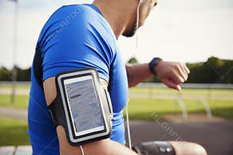 Male athlete wearing smartphone armband checking smartwatch