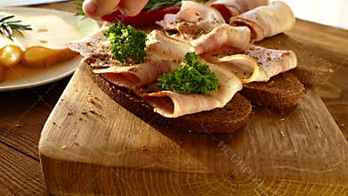 Sandwich with bacon and cheese. Black bread with bacon and spices. Cheese with holes on the plate. Thinly sliced pork