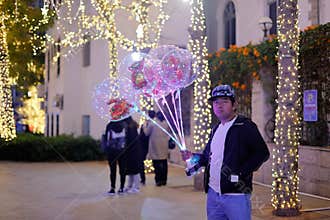 Men sell luminous balloons at night, srgb image