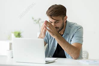 Nervous man thinking over problem trying to focus at work