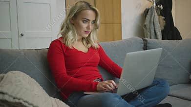 Smiling woman using laptop on sofa