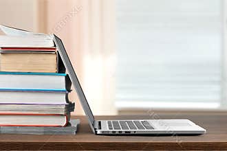 Stack of books with laptop on table
