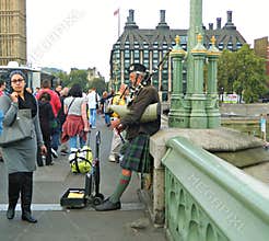 A Scottish Bagpipe Player on a Busy Westminster bridge in London