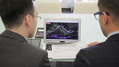 The two finance analytics work on the final report using the brand new laptop and draft.