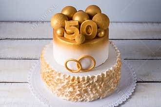 Beautiful cake for the 50th anniversary of the wedding decorated with gold balls and rings. Concept of festive desserts