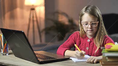 Lovely little girl e-learning with laptop at home