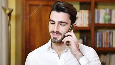 Handsome young man talking on telephone at home