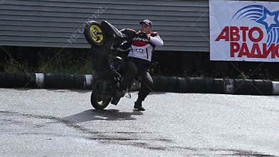 Stunt person rides scooter on one wheel and suddenly falls
